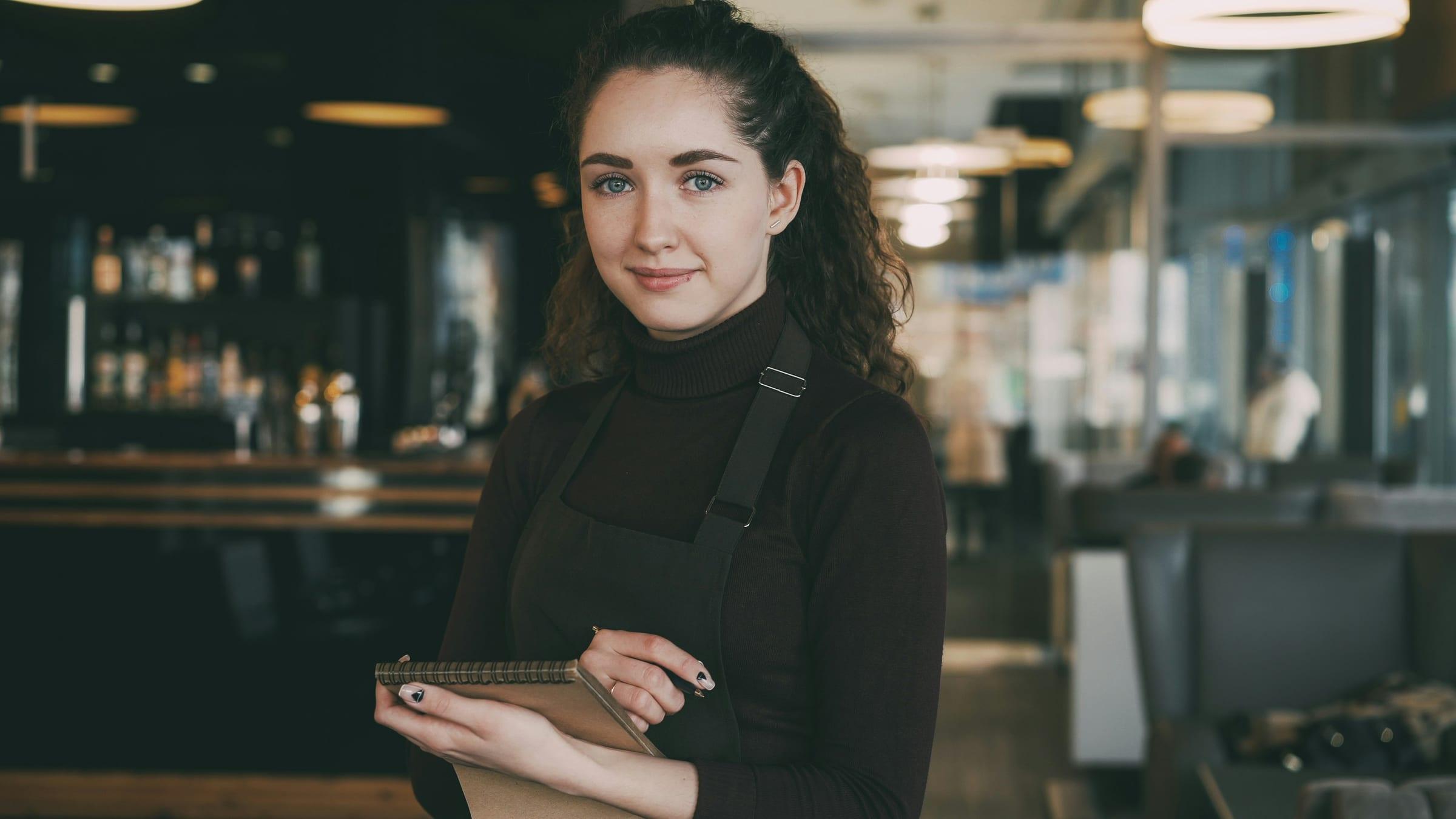 A duty manager standing behind the bar of a hospitality venue.