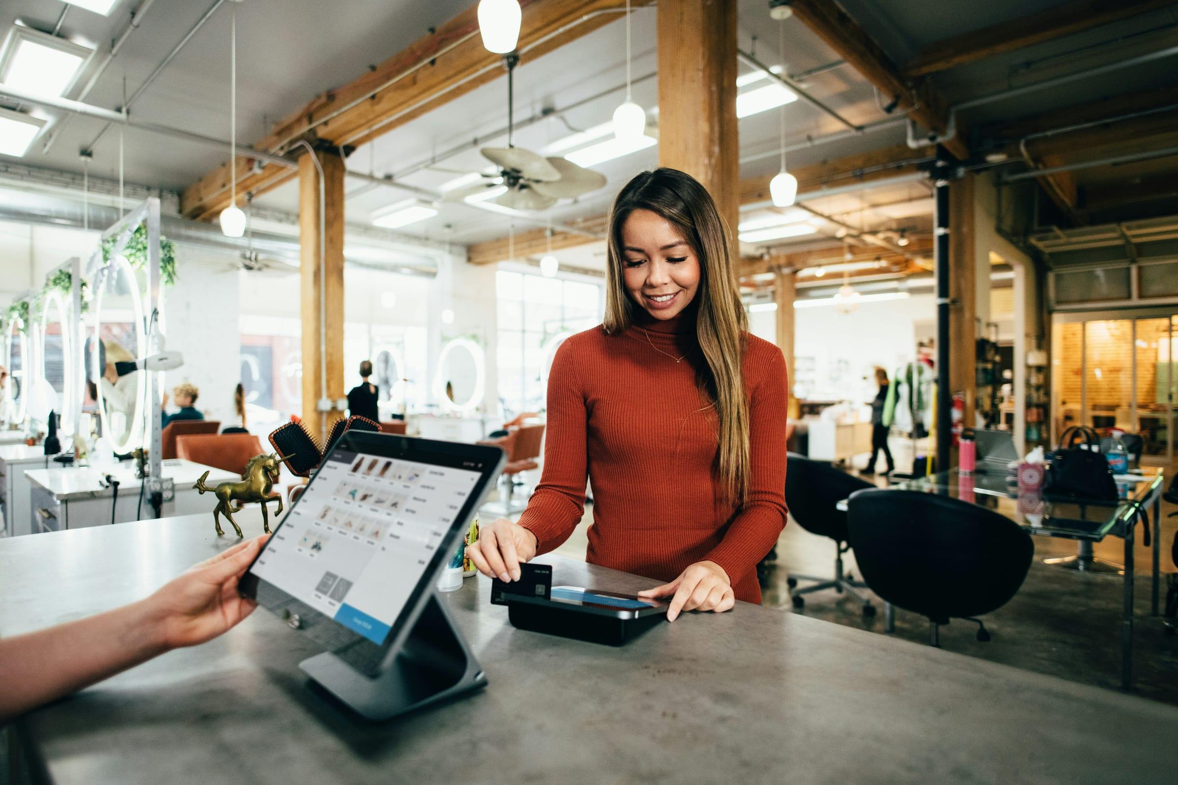 A retail assistant taking a card payment at the shop counter.