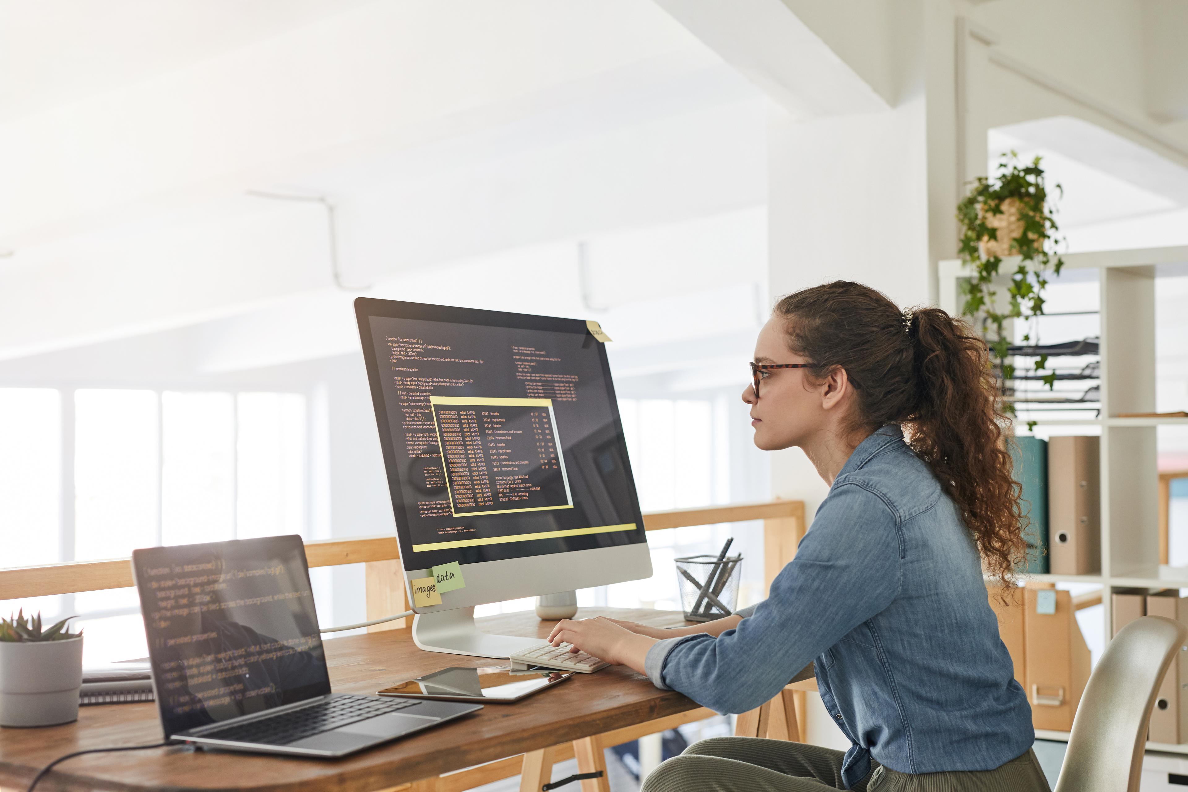 A person working at a computer in a bright, open-plan office.