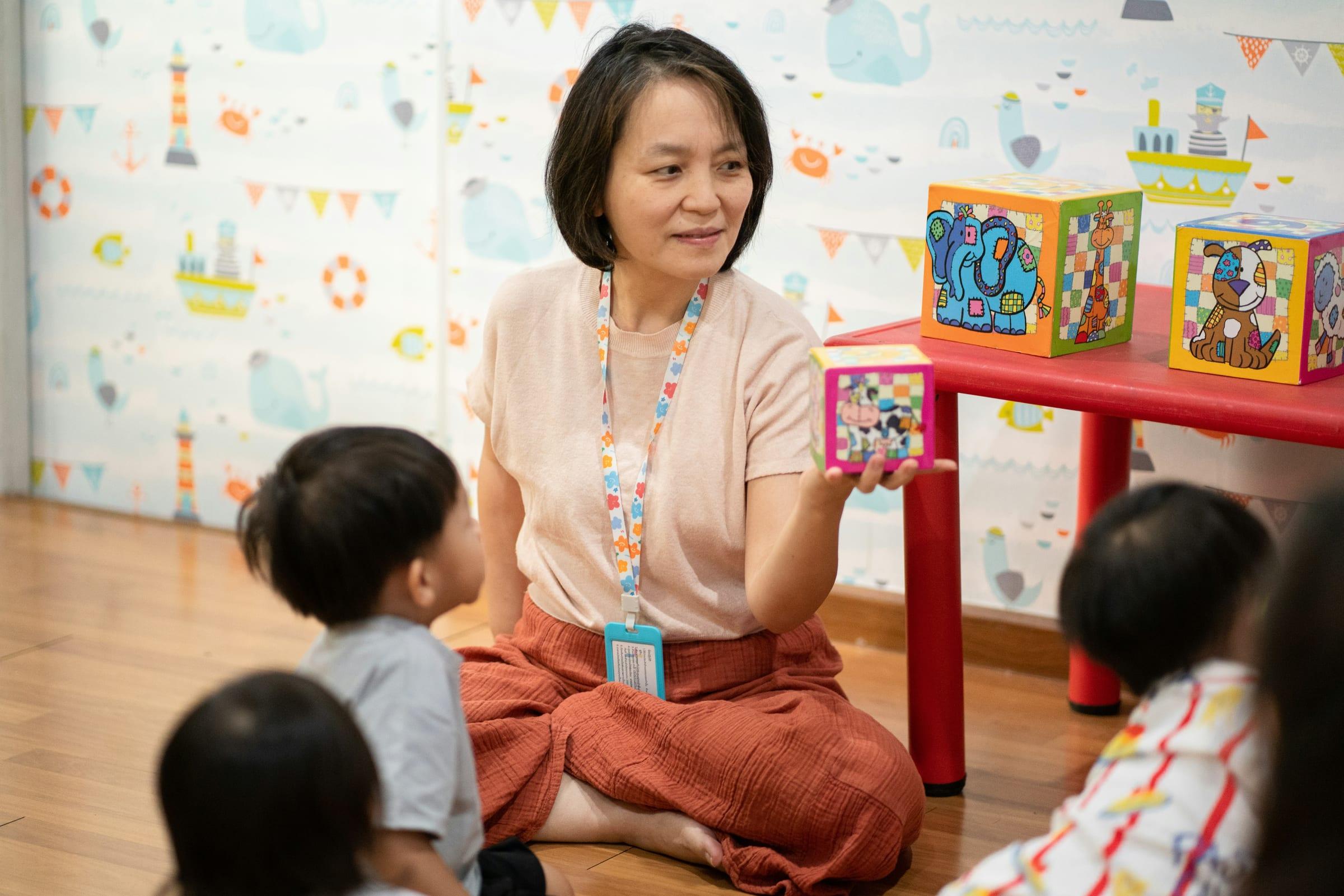 An early childhood educator working with young children in a bright learning space.