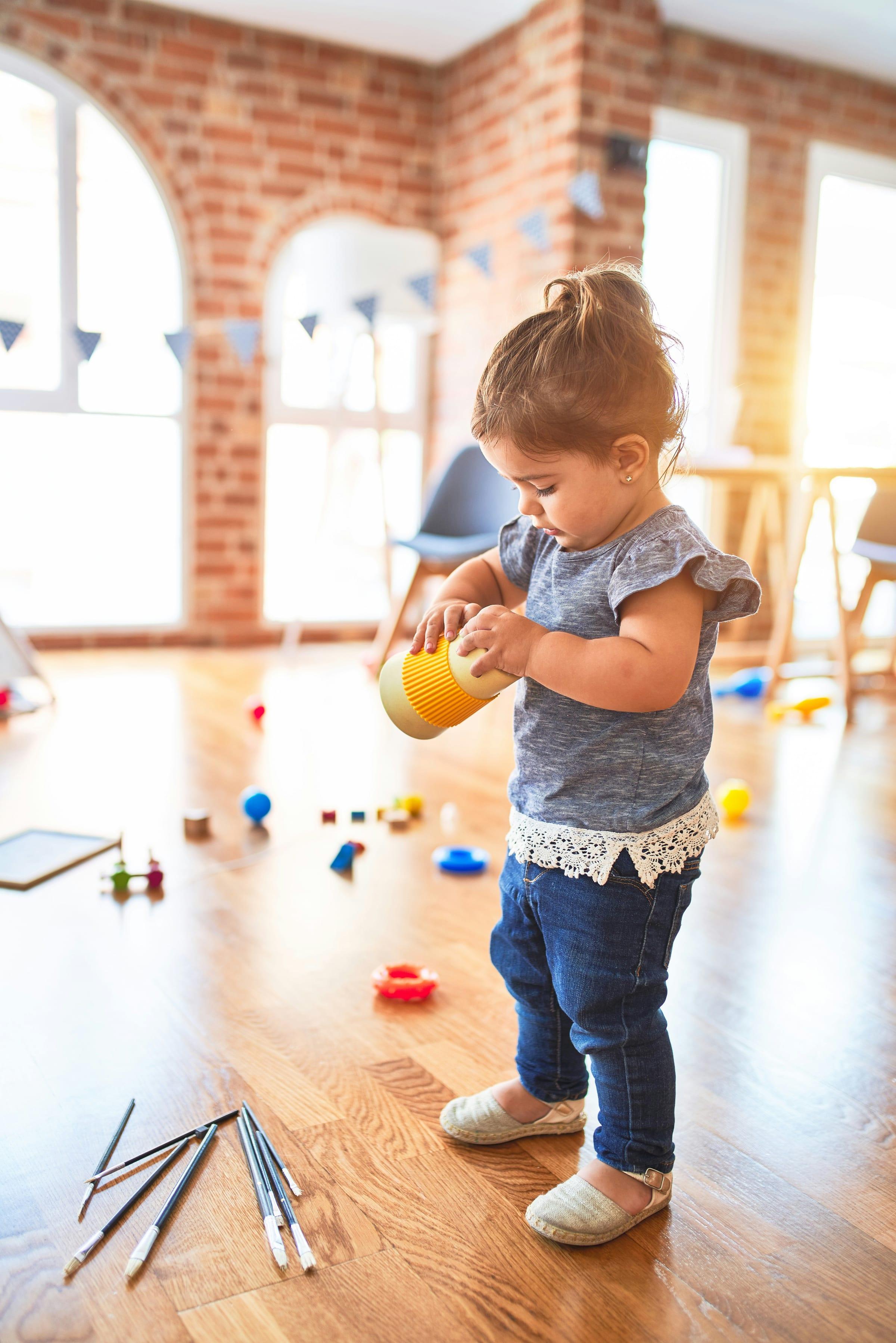 A young child playing with wooden blocks on the floor of a learning space.