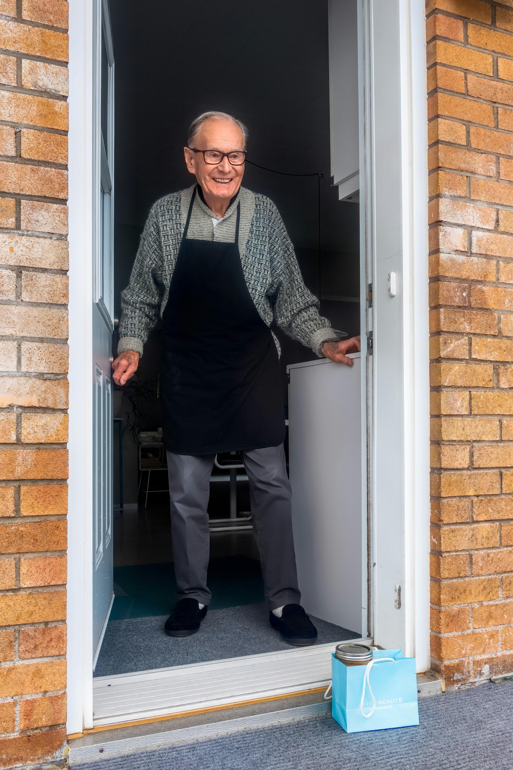 A support worker in an apron at the door of a residents room.