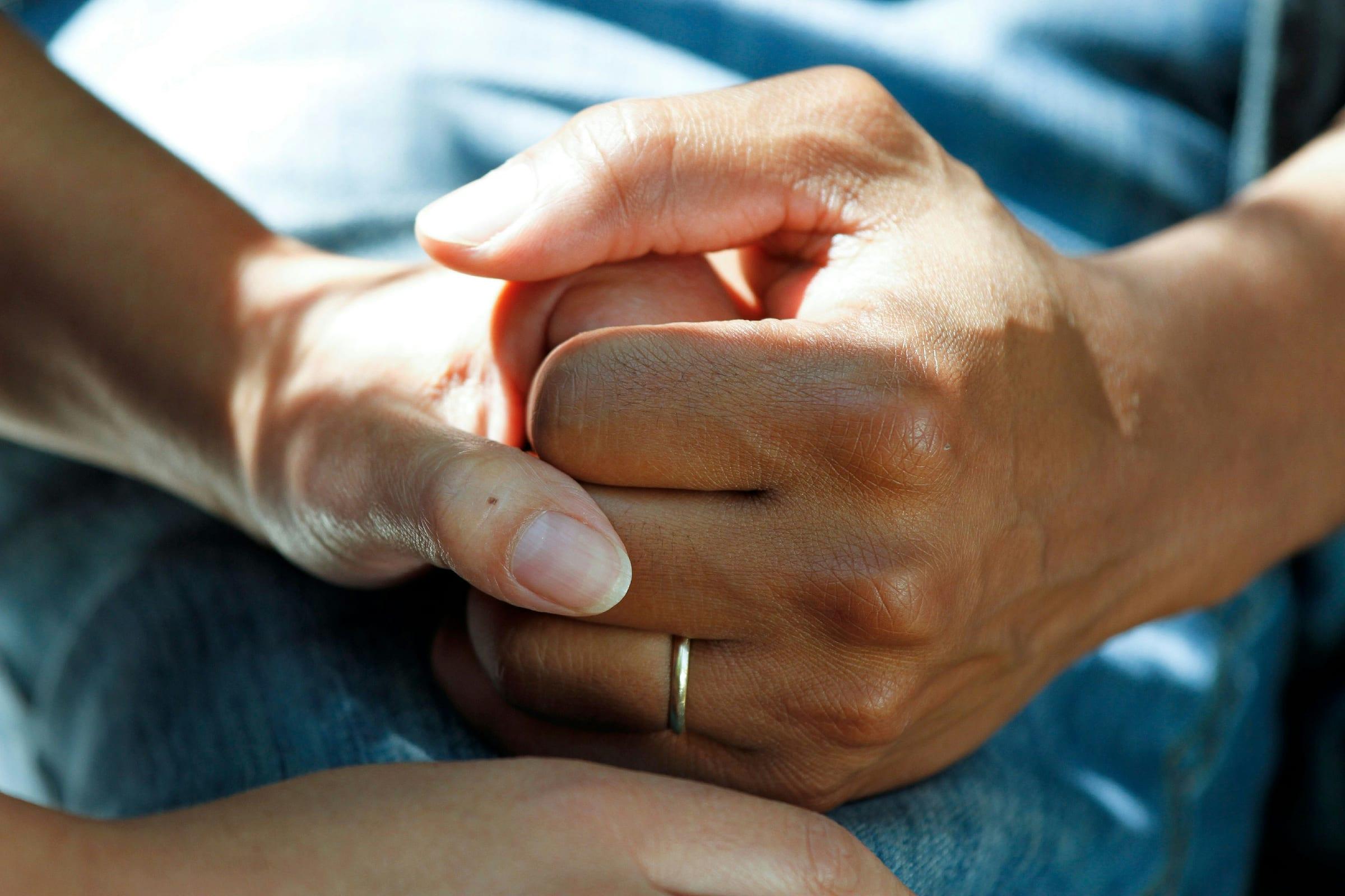 A carer holding the hands of an older person.