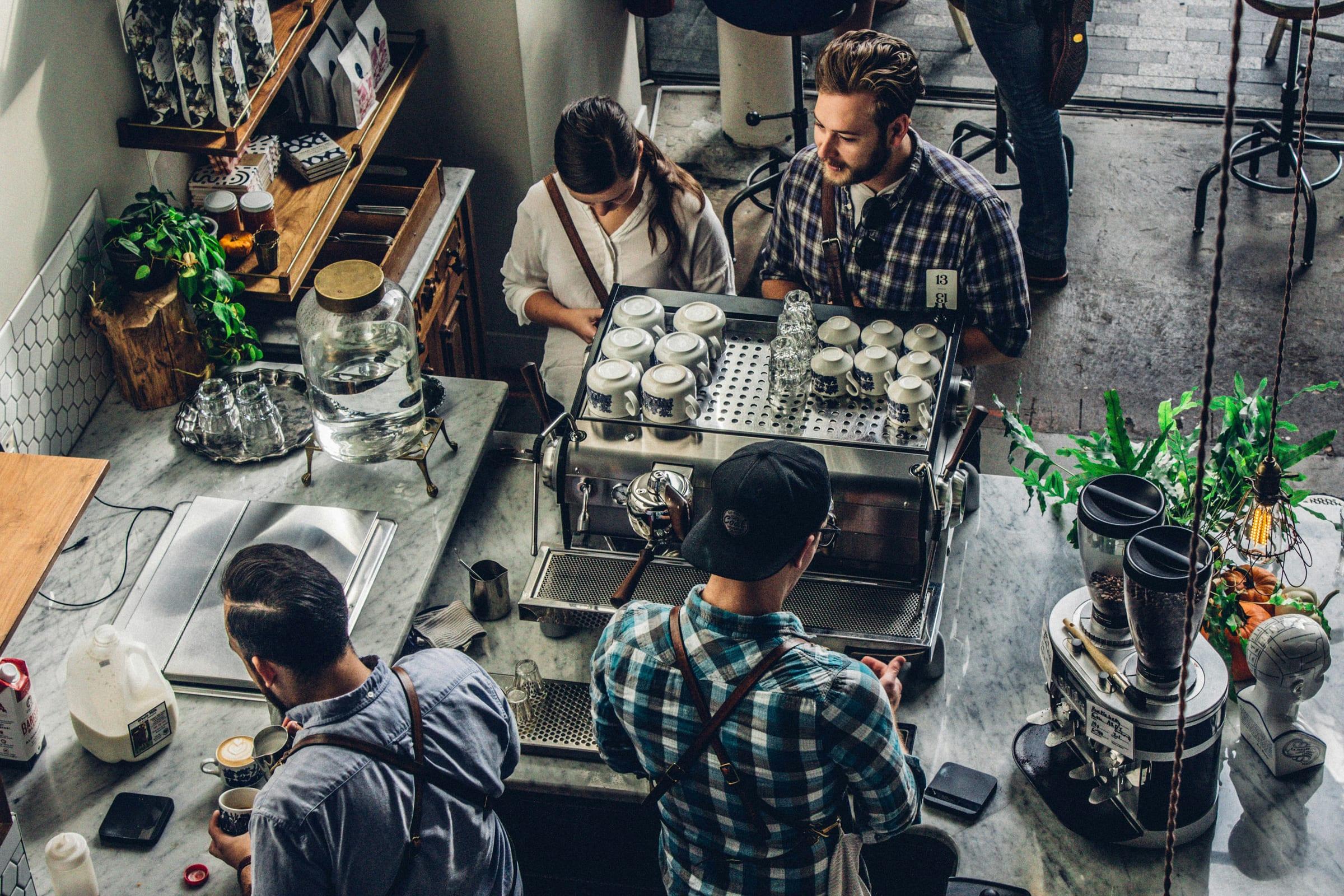 Baristas working an espresso machine, seen from above.