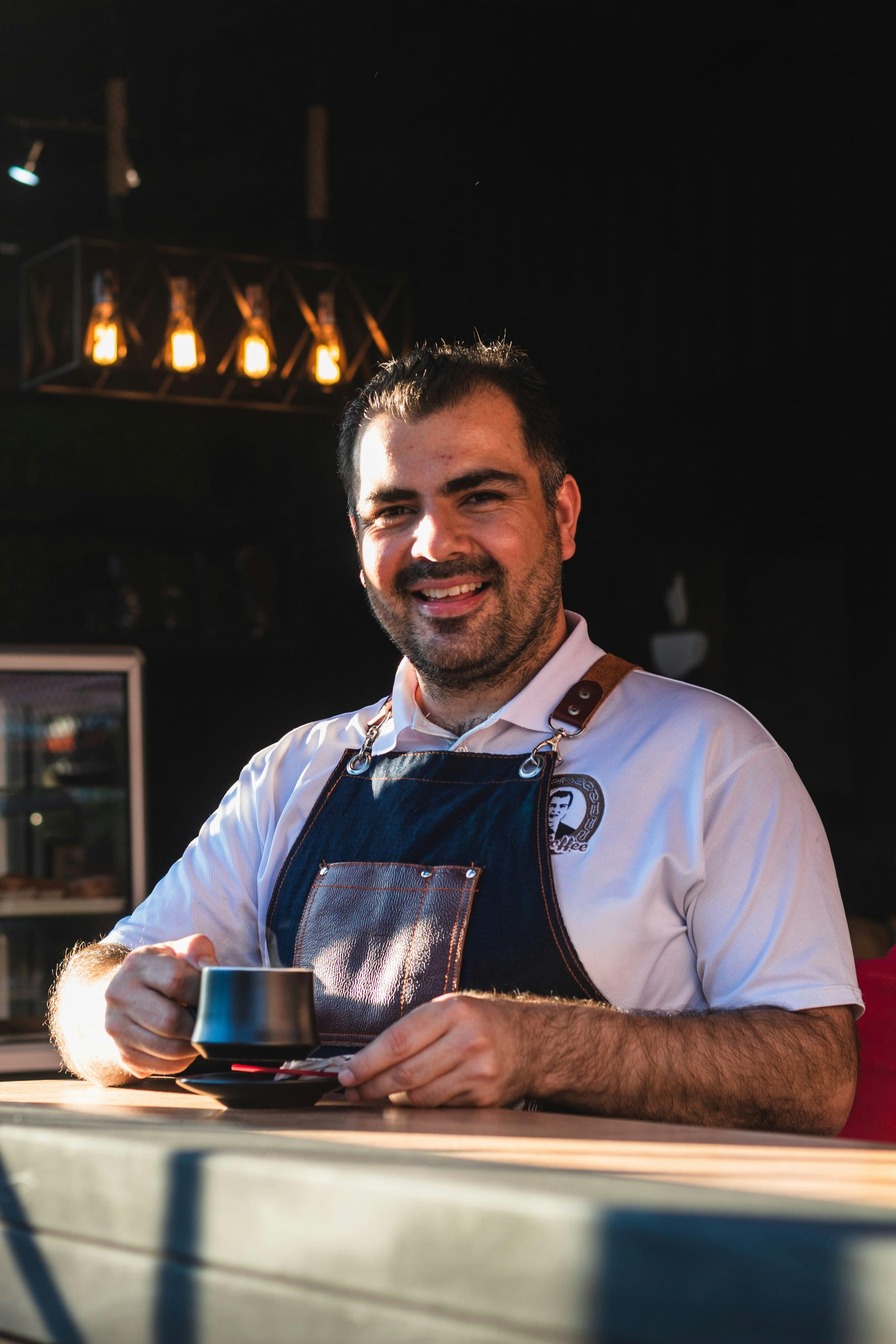 A barista in an apron standing behind the bar.